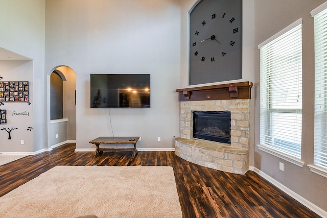 3544 Woods Estates Dr, Conroe, TX 77304 - living area with dark wood-type flooring, a high ceiling, a fireplace, arched walkways, and baseboards