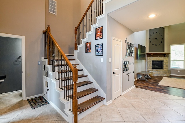 3544 Woods Estates Dr, Conroe, TX 77304 - stairs featuring a towering ceiling, tile patterned flooring, baseboards, and a fireplace