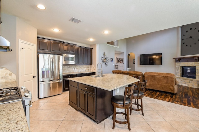 3544 Woods Estates Dr, Conroe, TX 77304 - kitchen featuring stainless steel appliances, a sink, open floor plan, a kitchen breakfast bar, and light tile patterned floors