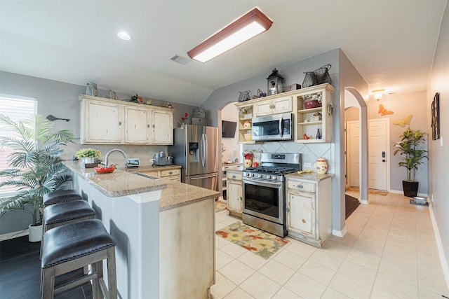 2238 Sterling Oaks Dr, Rosharon, TX 77583 - kitchen featuring appliances with stainless steel finishes, open shelves, a peninsula, arched walkways, and tasteful backsplash