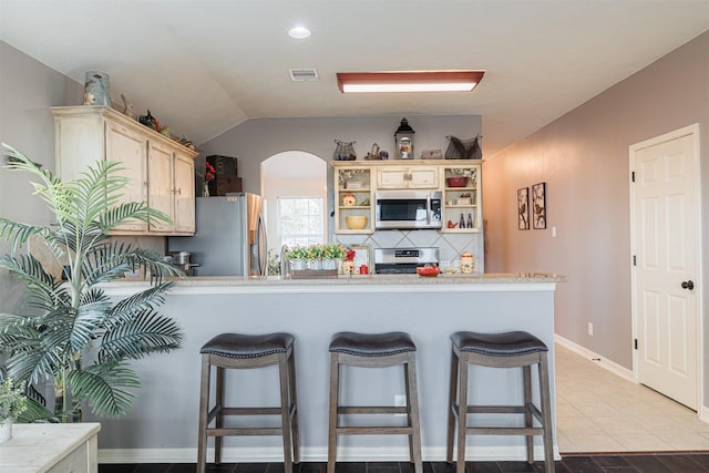 2238 Sterling Oaks Dr, Rosharon, TX 77583 - kitchen featuring appliances with stainless steel finishes, a peninsula, open shelves, a breakfast bar area, and arched walkways