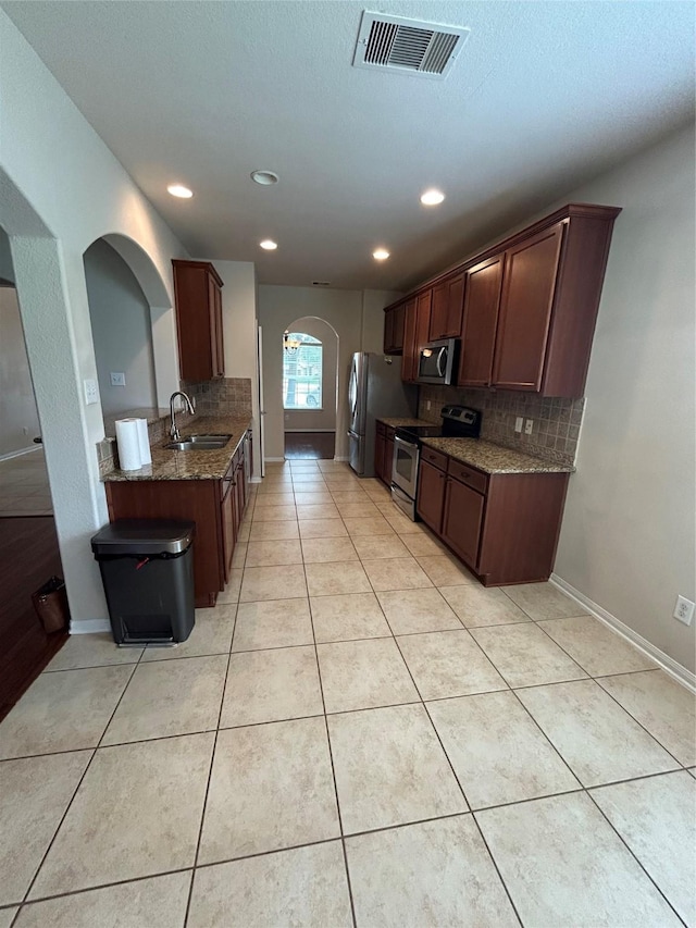 6015 Biltmore Ct, Rosenberg, TX 77471 - kitchen featuring stainless steel appliances, a sink, arched walkways, backsplash, and recessed lighting