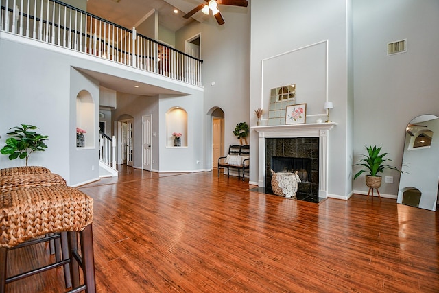 1638 Brookstone Ln, Sugar Land, TX 77479 - living room with arched walkways, ceiling fan, a high ceiling, a tiled fireplace, and wood finished floors