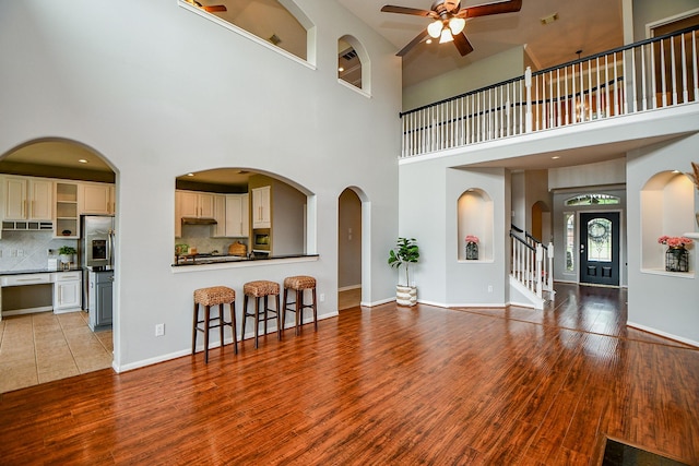 1638 Brookstone Ln, Sugar Land, TX 77479 - living area featuring a ceiling fan, wood finished floors, stairway, a towering ceiling, and baseboards
