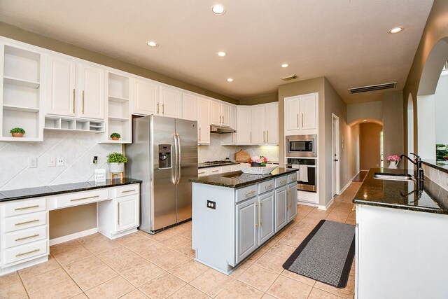 1638 Brookstone Ln, Sugar Land, TX 77479 - kitchen with appliances with stainless steel finishes, arched walkways, a sink, open shelves, and white cabinets