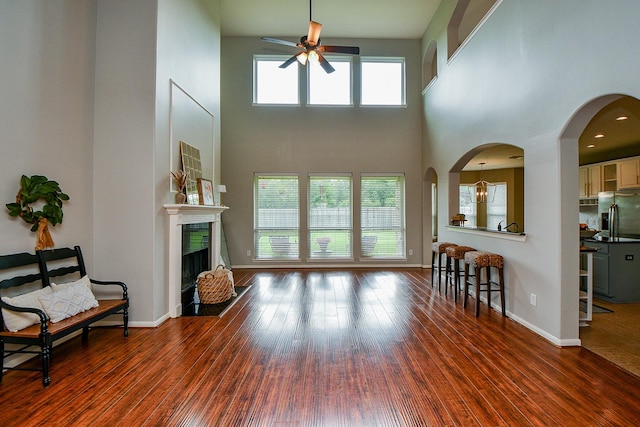 1638 Brookstone Ln, Sugar Land, TX 77479 - living area featuring a ceiling fan, a high ceiling, a fireplace, wood finished floors, and baseboards