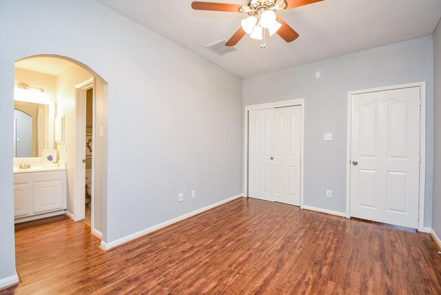 1638 Brookstone Ln, Sugar Land, TX 77479 - unfurnished bedroom with wood finished floors, a sink, a closet, arched walkways, and baseboards