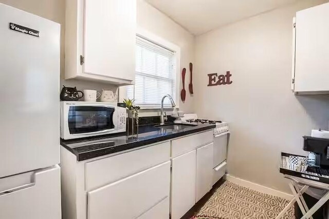 1017 Milner, College Station, TX 77840 - kitchen featuring white appliances, white cabinets, a sink, baseboards, and dark countertops