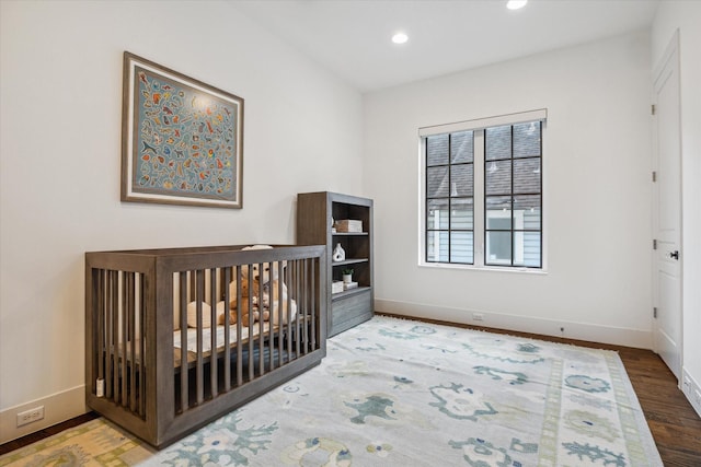 523 E 23rd St, Houston, TX 77008 - bedroom featuring baseboards, wood finished floors, recessed lighting, and a nursery area