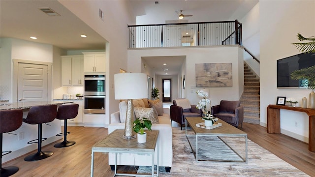 3539 Gore Creek Dr, Katy, TX 77494 - living area featuring stairs, light wood-style flooring, a ceiling fan, a towering ceiling, and recessed lighting