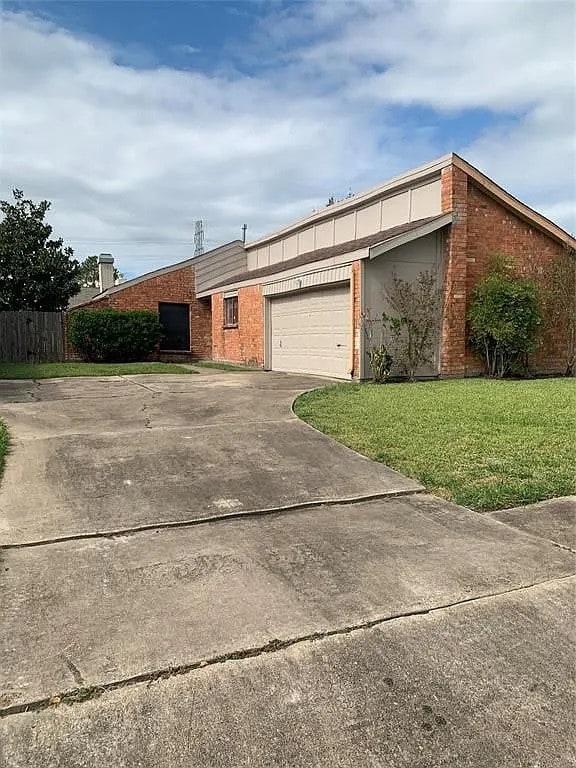 6826 Songbrook Dr, Houston, TX 77083 - view of front facade featuring a front yard, a garage, concrete driveway, and brick siding