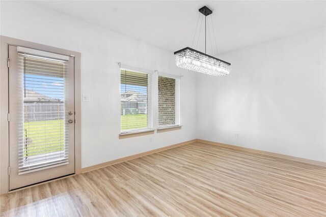 3434 Harper Meadow Ln, Missouri City, TX 77459 - unfurnished dining area with a chandelier, light wood-style flooring, and baseboards