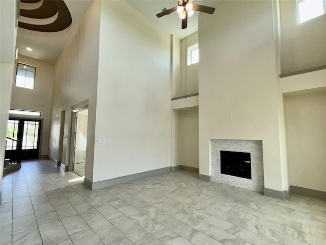 23422 Wilkinson Trl, Richmond, TX 77469 - unfurnished living room featuring a high ceiling, a ceiling fan, a fireplace, light marble finish floors, and baseboards
