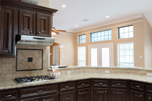1818 Janell Rene Cir, Deer Park, TX 77536 - kitchen with under cabinet range hood, gas stovetop, ceiling fan, dark brown cabinetry, and tasteful backsplash
