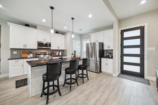 25747 Beaver Run Dr, Huffman, TX 77336 - kitchen featuring stainless steel appliances, tasteful backsplash, a breakfast bar, white cabinets, and recessed lighting