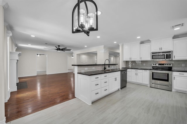 15905 Lakeview Dr, Jersey Village, TX 77040 - kitchen featuring appliances with stainless steel finishes, dark countertops, backsplash, white cabinets, and recessed lighting