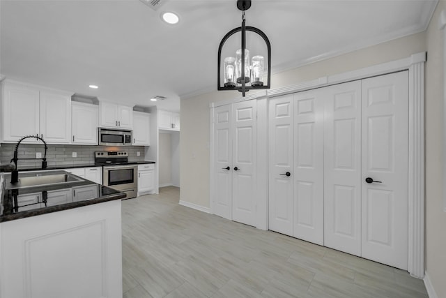 15905 Lakeview Dr, Jersey Village, TX 77040 - kitchen featuring appliances with stainless steel finishes, white cabinetry, a chandelier, decorative backsplash, and decorative light fixtures