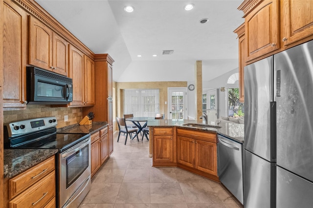 1722 Brook Grove Dr, Katy, TX 77450 - kitchen featuring appliances with stainless steel finishes, vaulted ceiling, a sink, dark stone countertops, and backsplash