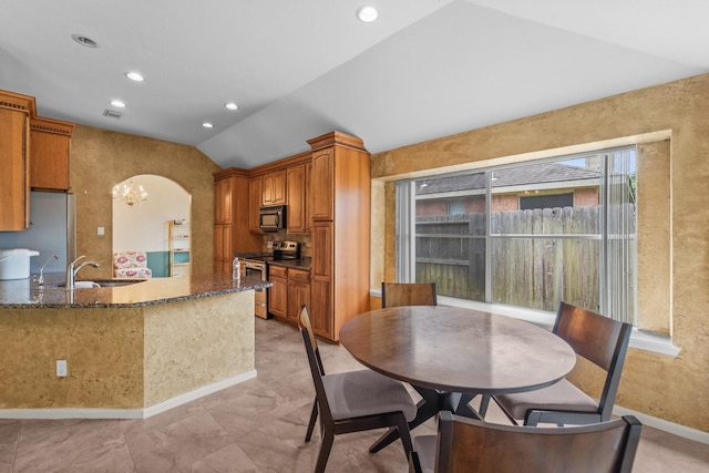 1722 Brook Grove Dr, Katy, TX 77450 - kitchen featuring appliances with stainless steel finishes, lofted ceiling, a sink, dark stone counters, and brown cabinets
