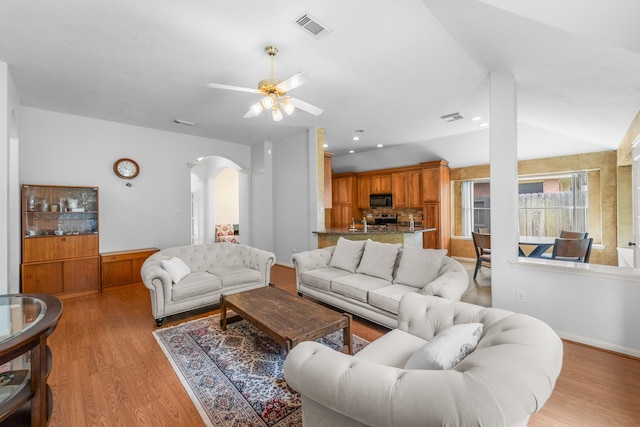 1722 Brook Grove Dr, Katy, TX 77450 - living area with arched walkways, a ceiling fan, light wood finished floors, and vaulted ceiling