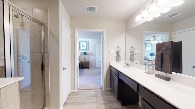 10288 Badger Run Ln, Magnolia, TX 77354 - ensuite bathroom featuring vanity, a shower stall, a ceiling fan, and wood finished floors