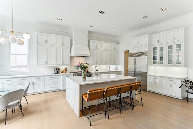 4613 Maple St, Bellaire, TX 77401 - kitchen with built in refrigerator, custom exhaust hood, ornamental molding, a kitchen breakfast bar, and white cabinetry