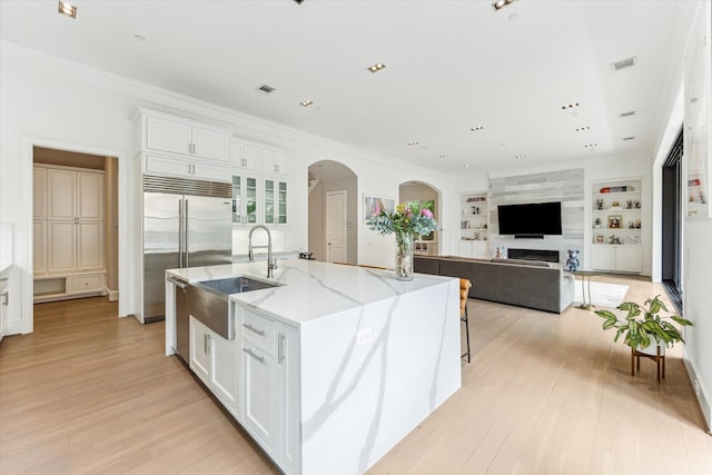 4613 Maple St, Bellaire, TX 77401 - kitchen featuring a sink, arched walkways, stainless steel built in fridge, white cabinets, and light stone countertops