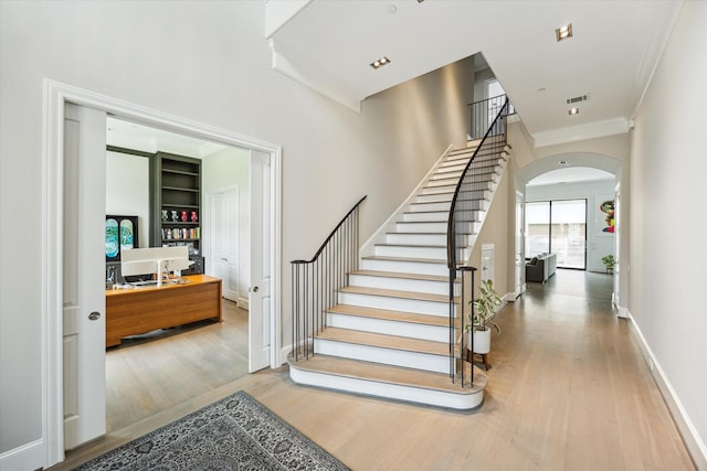 4613 Maple St, Bellaire, TX 77401 - stairway featuring wood finished floors, arched walkways, crown molding, built in shelves, and baseboards