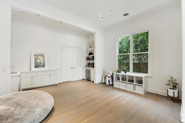 4613 Maple St, Bellaire, TX 77401 - living area with light wood-style flooring, crown molding, baseboards, and wine cooler