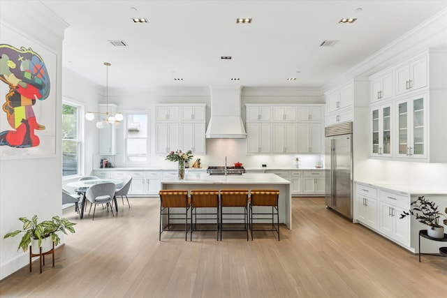 4613 Maple St, Bellaire, TX 77401 - kitchen with stainless steel built in refrigerator, custom exhaust hood, white cabinets, light countertops, and crown molding