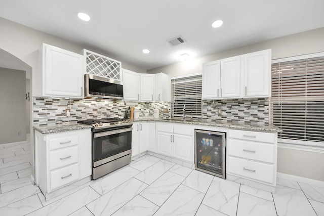 8707 Tartan Walk Ln, Houston, TX 77075 - kitchen featuring beverage cooler, appliances with stainless steel finishes, light marble finish flooring, white cabinetry, and recessed lighting