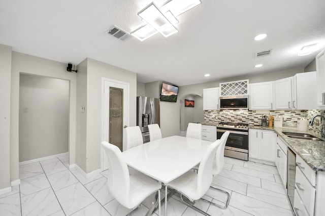8707 Tartan Walk Ln, Houston, TX 77075 - dining area with light marble finish floors, baseboards, recessed lighting, and arched walkways