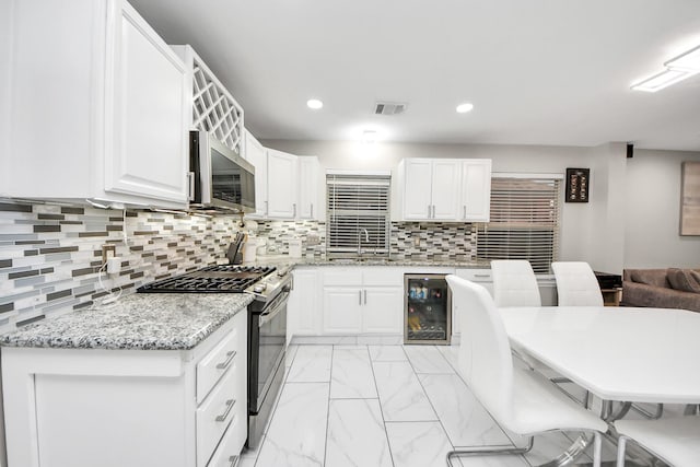 8707 Tartan Walk Ln, Houston, TX 77075 - kitchen with appliances with stainless steel finishes, wine cooler, a sink, white cabinetry, and recessed lighting