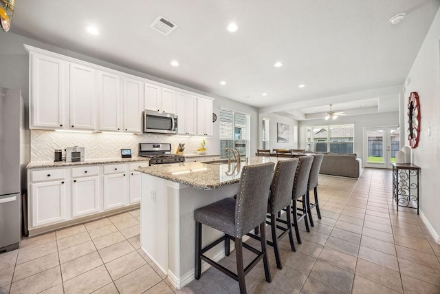 15210 Monal Trie Dr, Humble, TX 77346 - kitchen featuring stainless steel appliances, light tile patterned flooring, tasteful backsplash, a sink, and white cabinetry