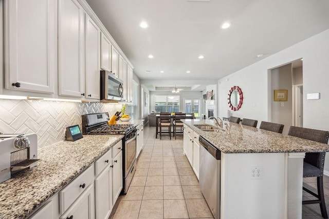 15210 Monal Trie Dr, Humble, TX 77346 - kitchen with stainless steel appliances, a kitchen bar, a sink, recessed lighting, and decorative backsplash