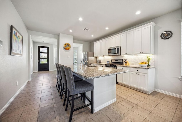 15210 Monal Trie Dr, Humble, TX 77346 - kitchen featuring appliances with stainless steel finishes, light tile patterned floors, decorative backsplash, a breakfast bar, and an island with sink