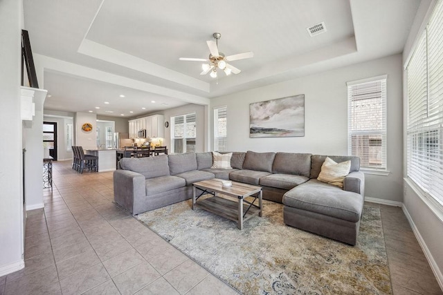 15210 Monal Trie Dr, Humble, TX 77346 - living room featuring a tray ceiling, ceiling fan, baseboards, and light tile patterned floors
