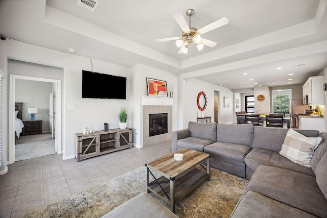 15210 Monal Trie Dr, Humble, TX 77346 - living area featuring light tile patterned flooring, ceiling fan, a fireplace, a raised ceiling, and baseboards