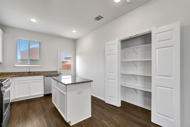 25919 Llano Knoll Ln, Katy, TX 77493 - kitchen featuring appliances with stainless steel finishes, dark stone countertops, dark wood-style flooring, white cabinetry, and recessed lighting
