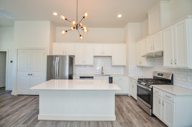 9414 Kerrwood Ln Unit B, Houston, TX 77080 - kitchen featuring appliances with stainless steel finishes, a sink, under cabinet range hood, a center island, and a chandelier