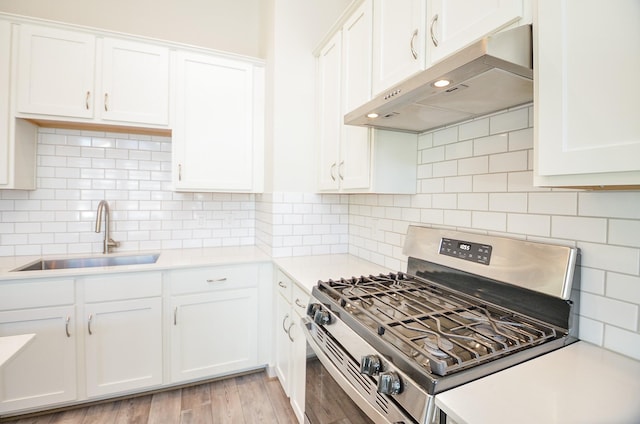 9414 Kerrwood Ln Unit B, Houston, TX 77080 - kitchen with stainless steel gas stove, a sink, under cabinet range hood, light countertops, and white cabinets