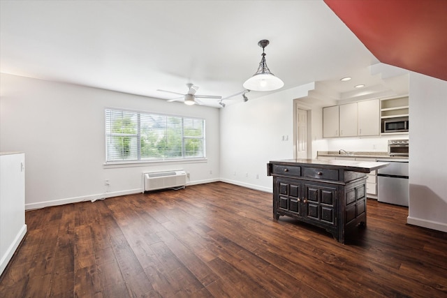 4521 Palmetto St, Bellaire, TX 77401 - kitchen featuring appliances with stainless steel finishes, a kitchen island, dark wood finished floors, a ceiling fan, and baseboards