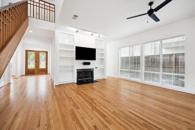 4521 Palmetto St, Bellaire, TX 77401 - unfurnished living room with light wood-type flooring, ceiling fan, stairway, built in shelves, and a high end fireplace