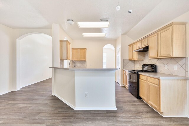 6431 Bright Falls Ln, Katy, TX 77449 - kitchen with black electric range oven, under cabinet range hood, light brown cabinets, arched walkways, and wood finished floors