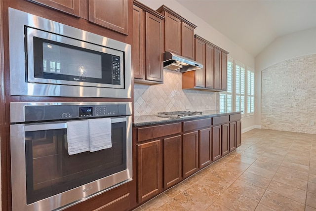 2110 Aztec Thrush Dr, Katy, TX 77494 - kitchen with stainless steel appliances, lofted ceiling, under cabinet range hood, backsplash, and dark stone counters
