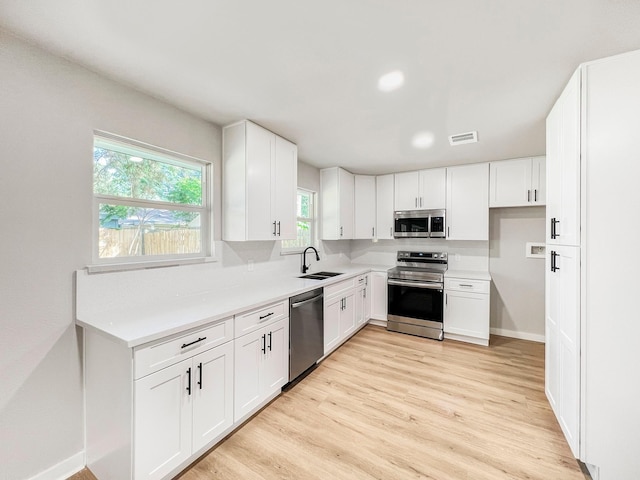 4926 Adonis Dr, Spring, TX 77373 - kitchen featuring appliances with stainless steel finishes, light wood-type flooring, white cabinetry, light countertops, and a sink