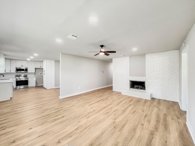 4926 Adonis Dr, Spring, TX 77373 - unfurnished living room featuring ceiling fan, a brick fireplace, baseboards, light wood-style floors, and recessed lighting