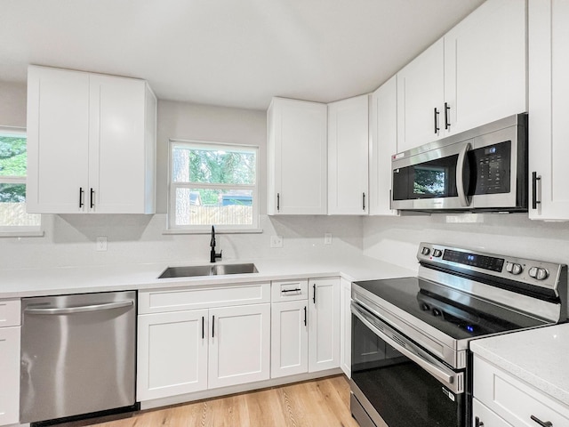 4926 Adonis Dr, Spring, TX 77373 - kitchen featuring stainless steel appliances, a sink, light wood-style flooring, light countertops, and white cabinetry