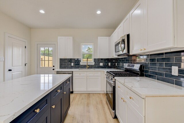 8149 Talton St B, Unit A, Houston, TX 77028 - kitchen featuring appliances with stainless steel finishes, white cabinets, tasteful backsplash, light wood-type flooring, and a sink