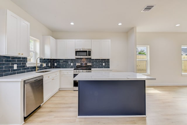 8149 Talton St B, Unit A, Houston, TX 77028 - kitchen with appliances with stainless steel finishes, a sink, light wood finished floors, a kitchen island, and recessed lighting